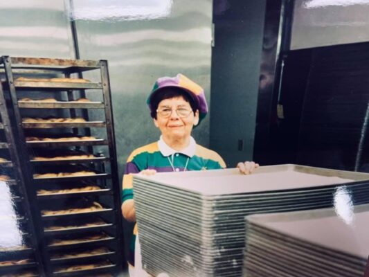 woman in mardi gras attire baking king cake