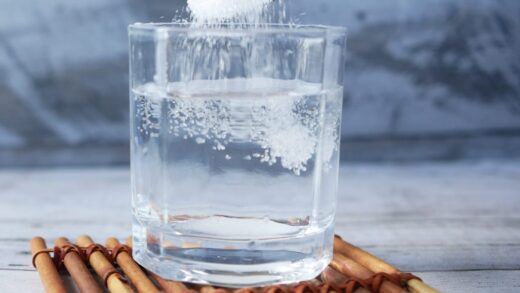 glass of water with sugar being poured into it