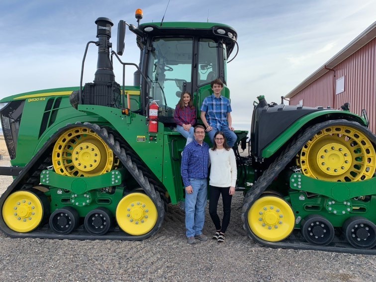 Entire family in front of tractor.